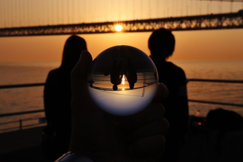橋の向こうの夕暮れに沈む太陽と眺めるカップル