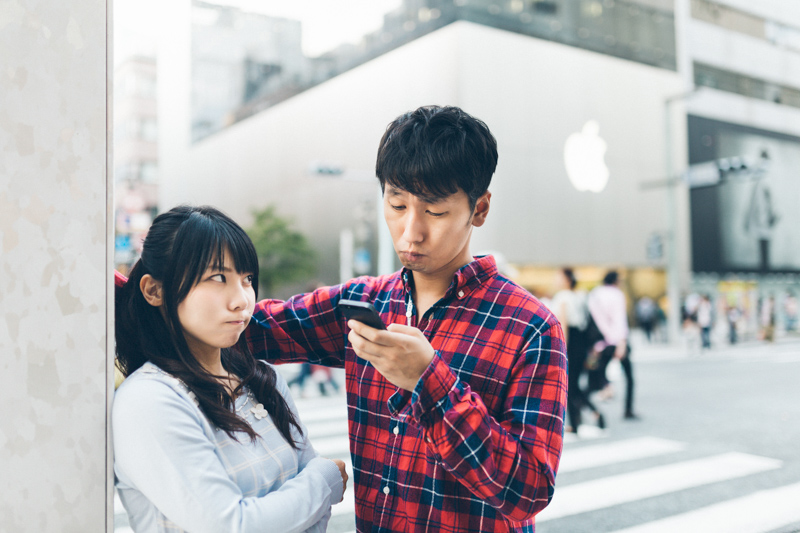 スマホをいじる男性に不機嫌な女性