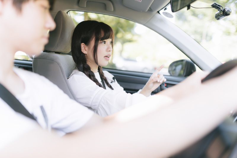 女性に道案内されながら運転する男性