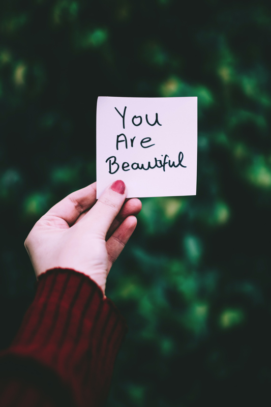 You are beatifulと書かれた紙を持つ女性の手