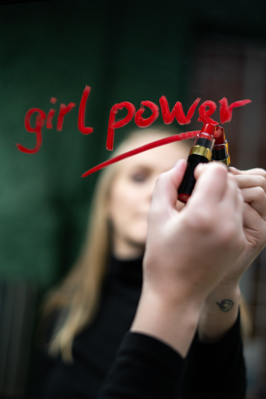 girl powerと鏡に口紅で書く女性