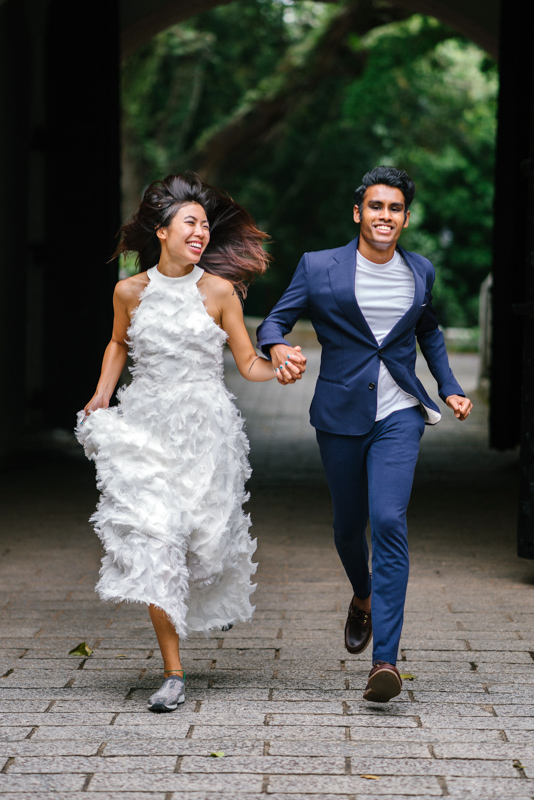 駆け出すドレス姿の新婦とタキシード姿の新郎